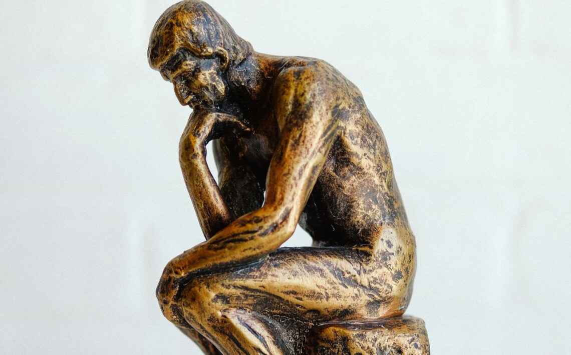 Escultura de un pensador sentado, símbolo de reflexión sobre el protocolo institucional